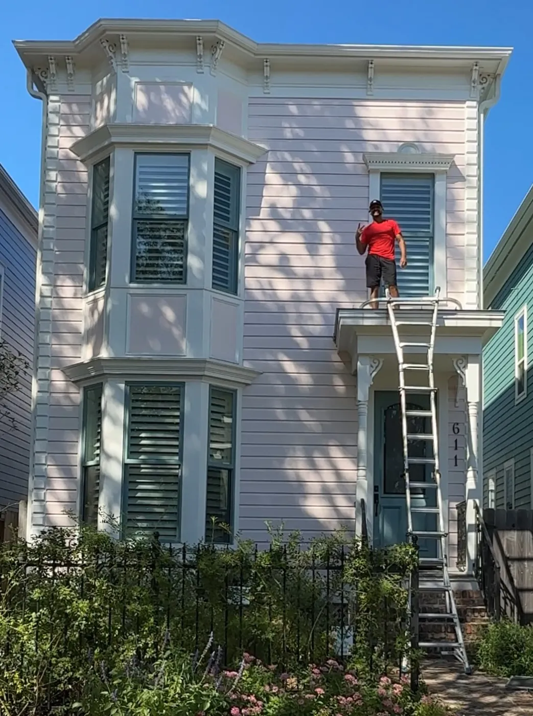 Window cleaner on a ladder at a two-story home's second-floor window