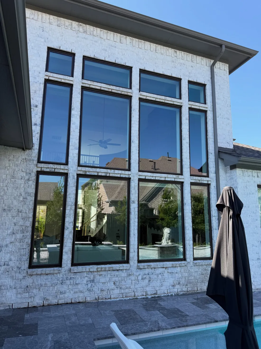Tall clean windows on a white brick home beside a pool